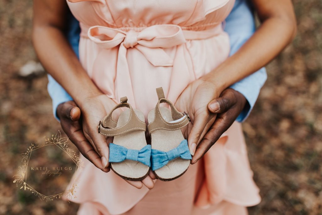 couple holding baby shoes maternity photos