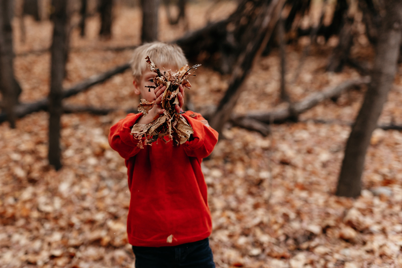 kid blowing fall leaves in photos